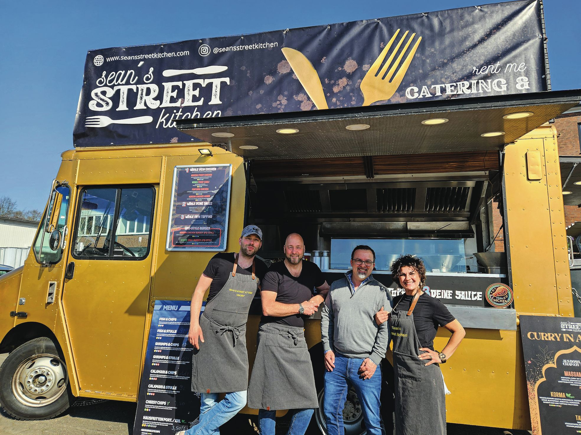 Eine Gruppe von Menschen steht vor einem Foodtruck.