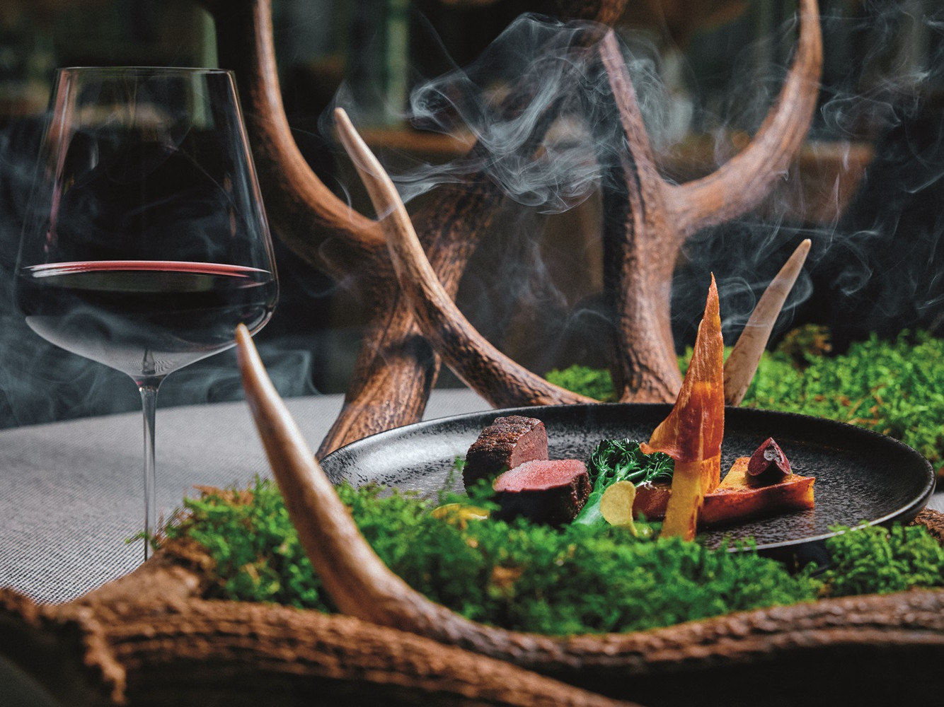 Ein Teller mit Fleisch und Gemüse neben einem Glas Wein.