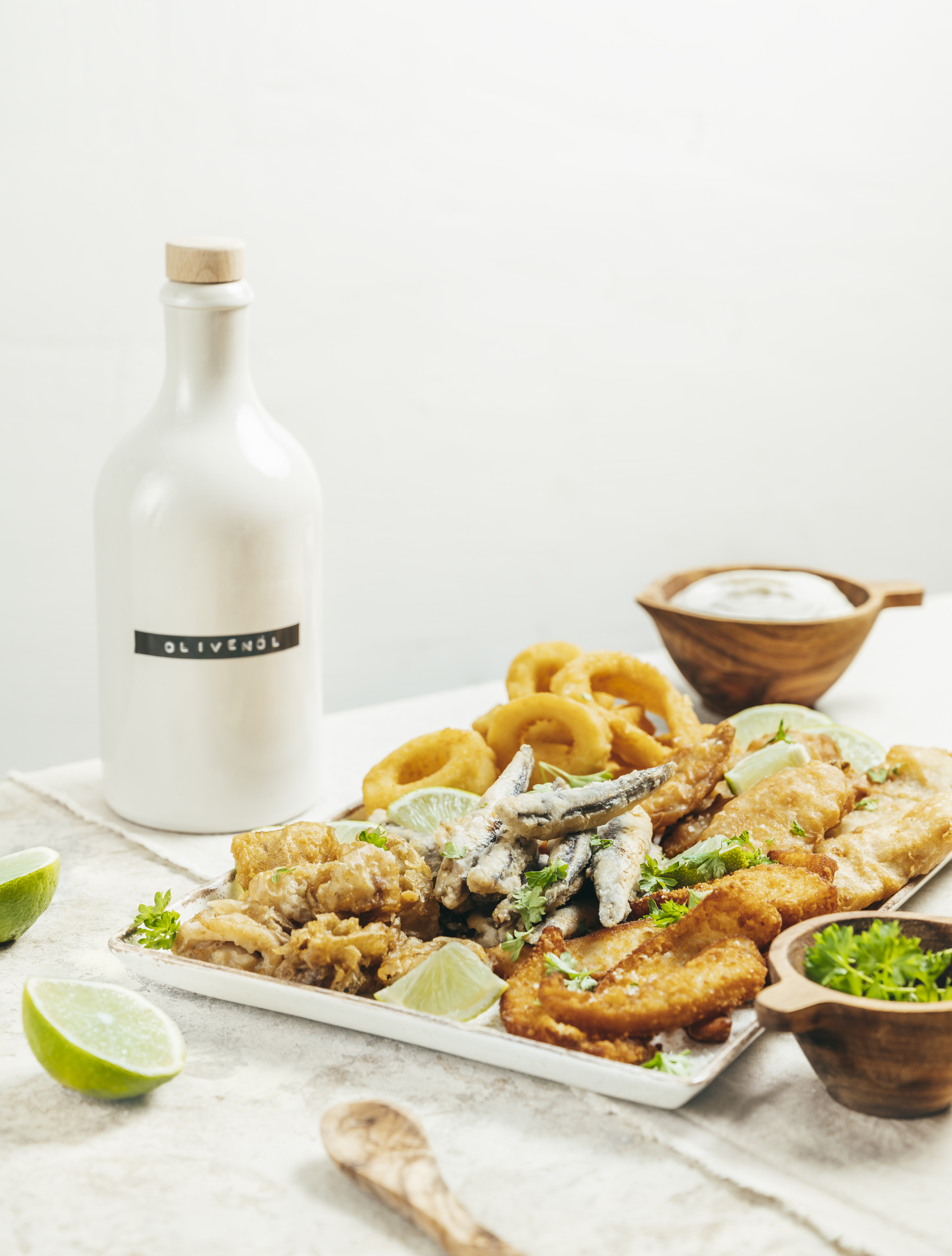 Eine Platte mit Fischspezialitäten in einem Setting mit Olivenöl, Salz und Kräutern.