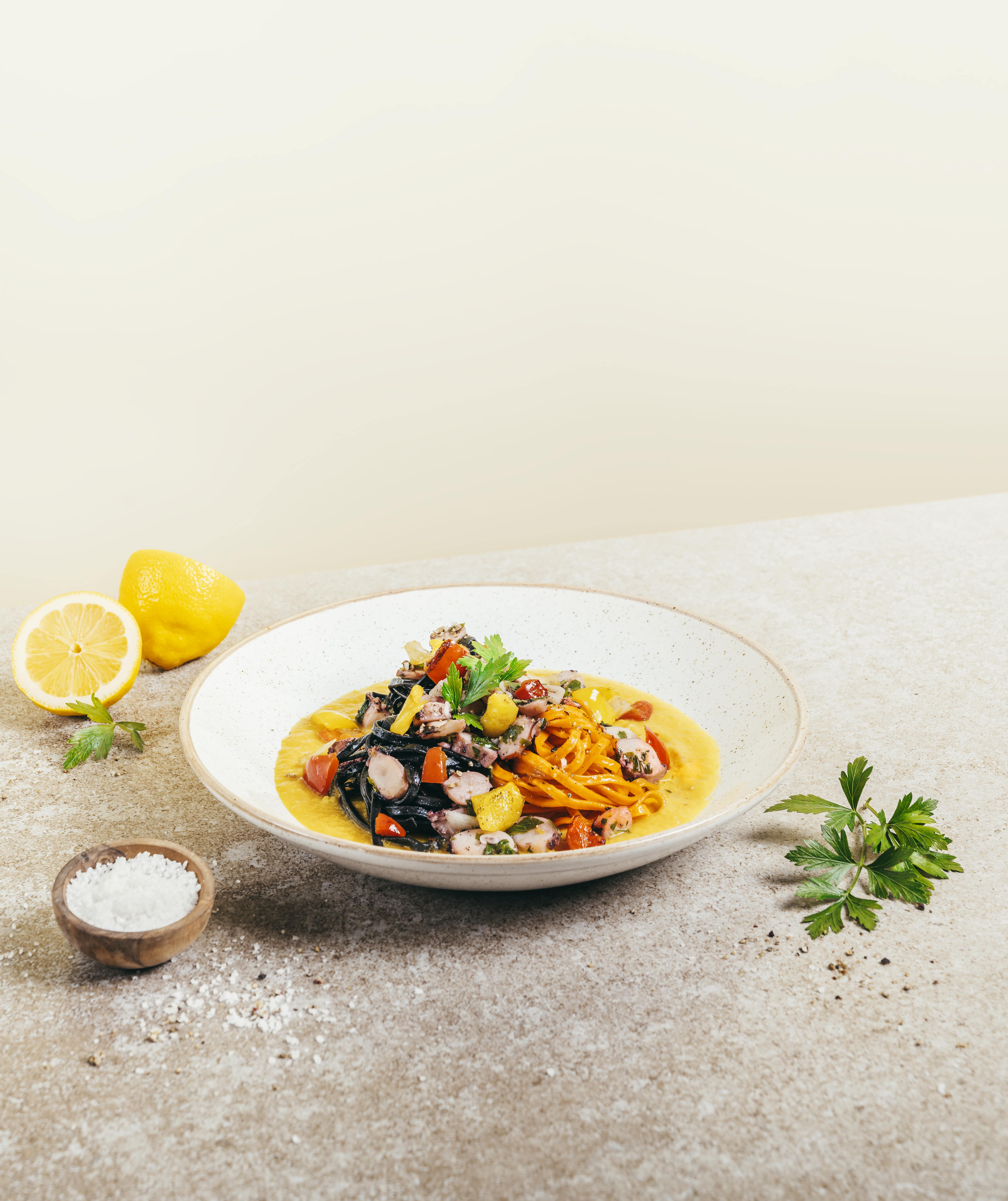 Ein Teller mit einem Pastagericht mit Riesenkalmar auf einem Tisch.