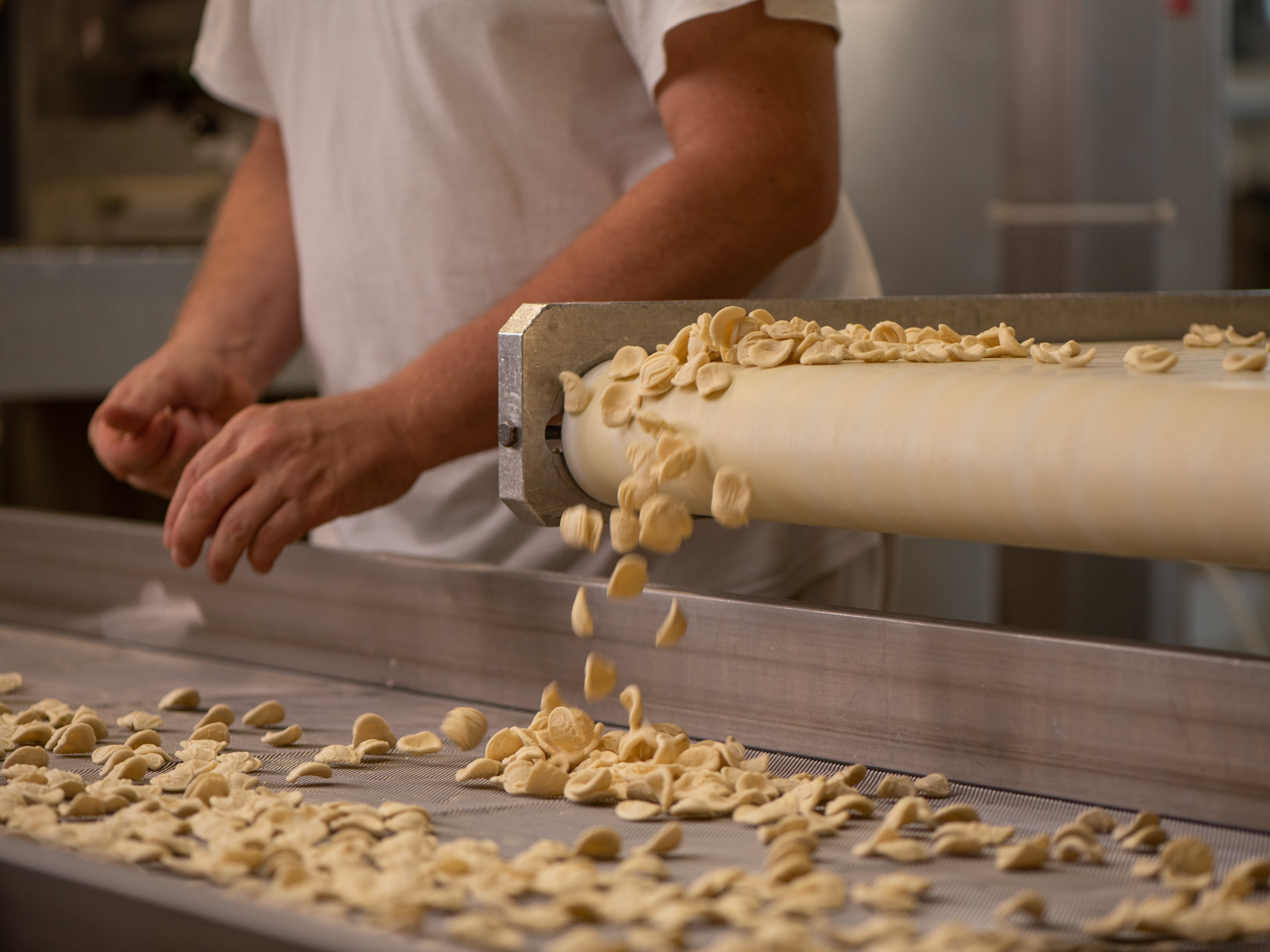 Eine Person arbeitet an einer Maschine zur Pastaherstellung.