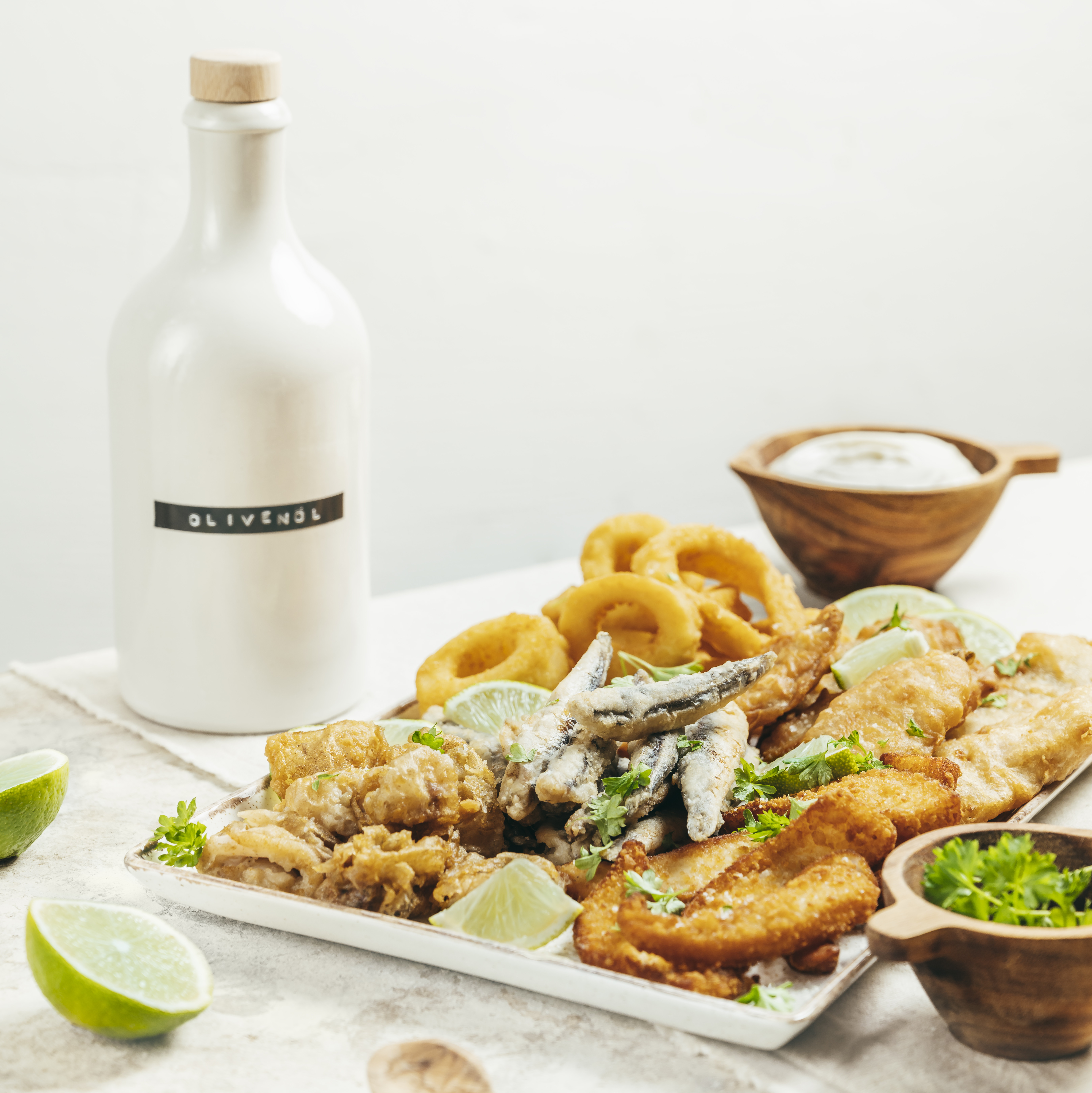 Eine Platte mit Fischspezialitäten, dekoriert in einem Setting aus Olivenöl, Kräutern und Salz. 