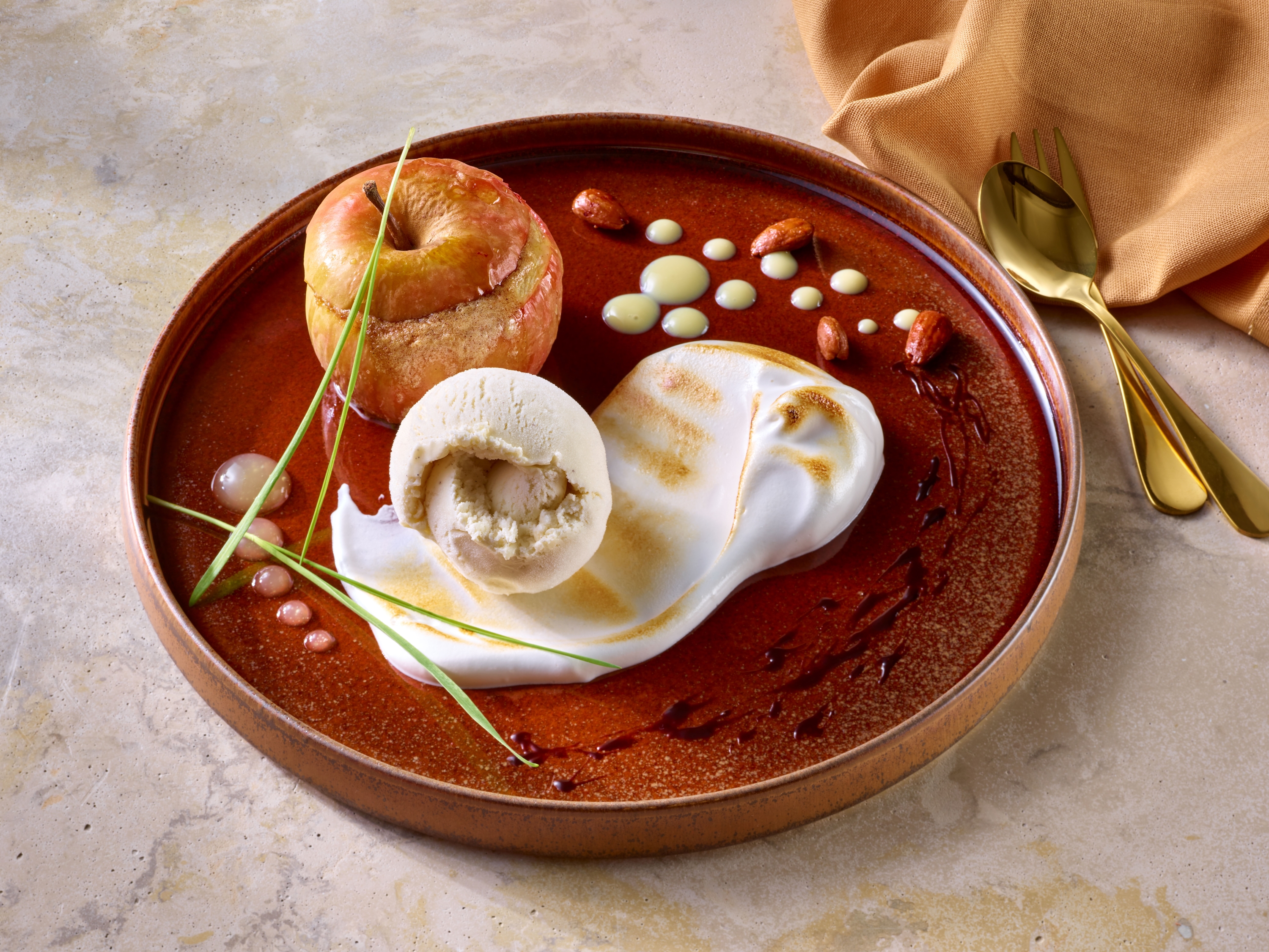 Bratapfel Dessert mit Eis auf einem edlen Teller angerichtet.